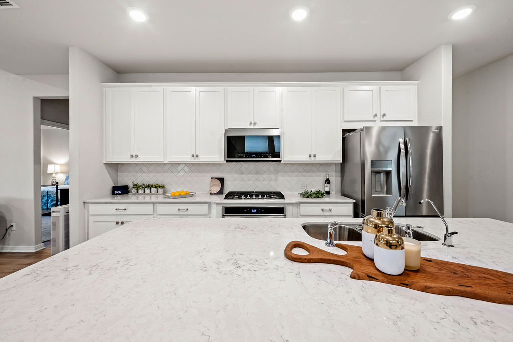 2417 Roosevelt Road Leander, TX 78641 - Photo 12 of 40 Kitchen featuring light stone counters, white cabinetry, appliances with stainless steel finishes, decorative backsplash, and recessed lighting