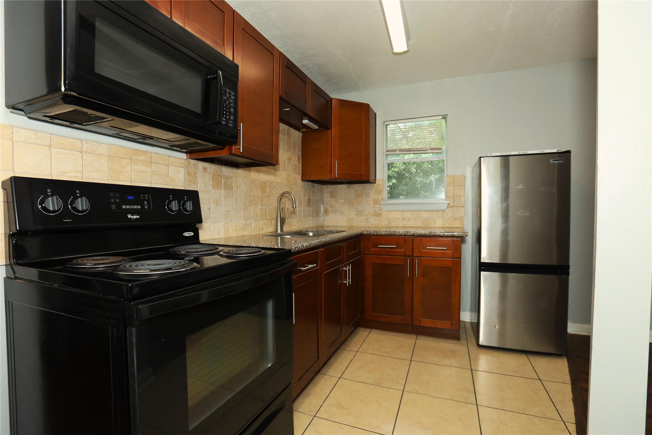 713 South Valderas Street Angleton, TX 77515 - Photo 4 of 10 a kitchen with stainless steel appliances granite countertop a stove microwave and refrigerator