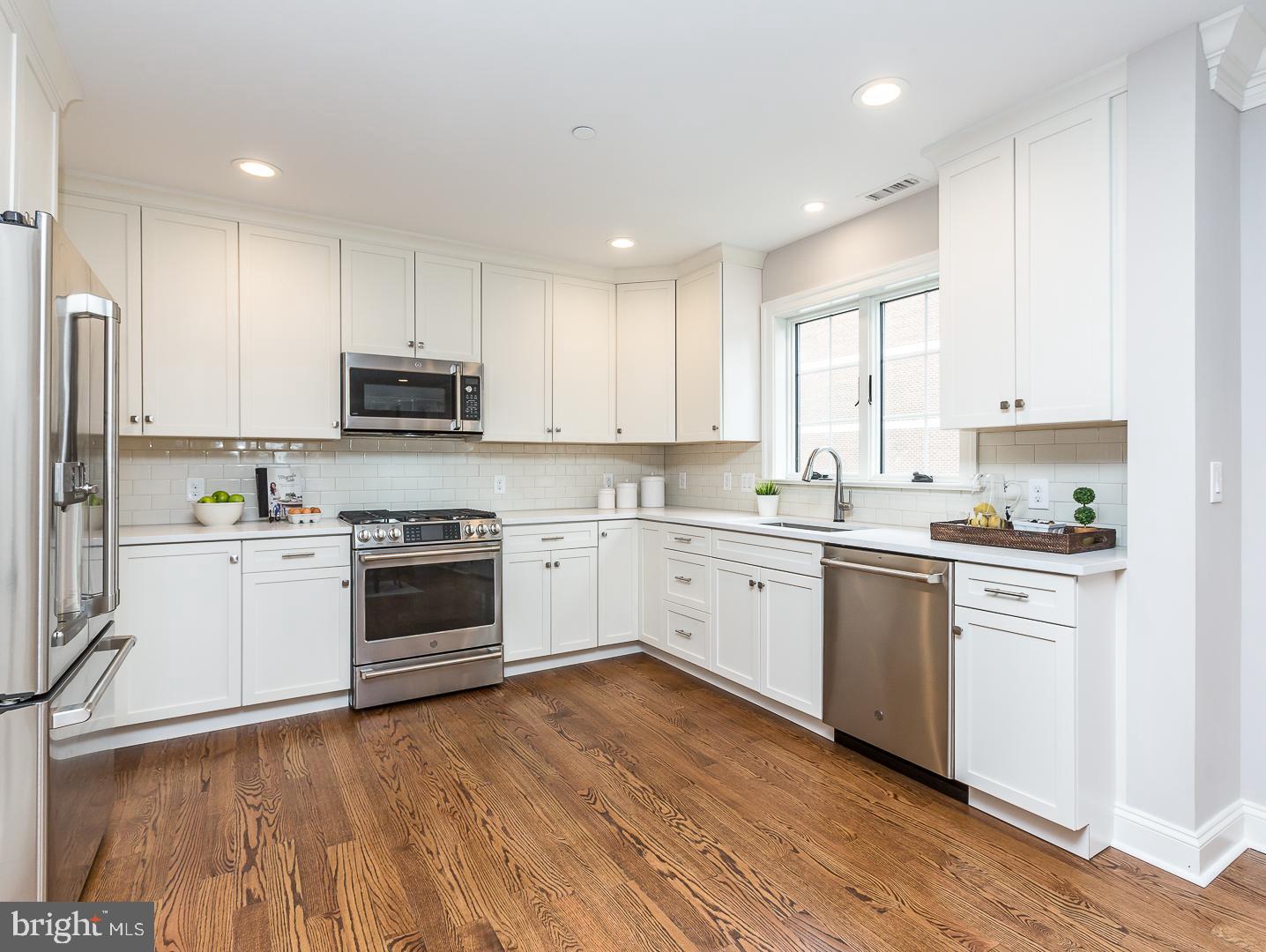 111 West Montgomery Avenue, Unit 107 Ardmore, PA 19003 - Photo 8 of 44 a kitchen with a white cabinets a sink a window and stainless steel appliances