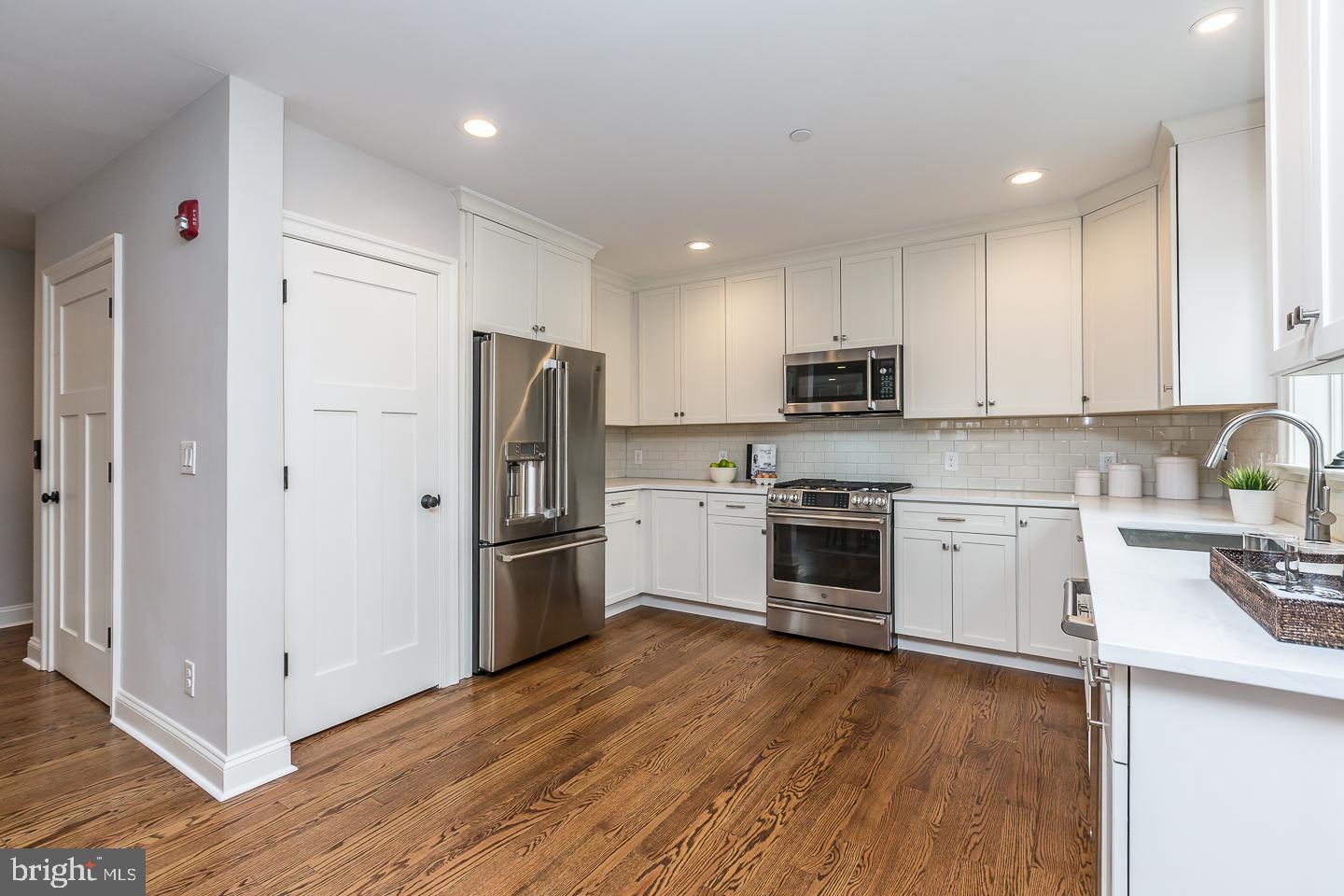 111 West Montgomery Avenue, Unit 107 Ardmore, PA 19003 - Photo 9 of 44 a kitchen with a refrigerator a stove top oven a sink and dishwasher with wooden floor