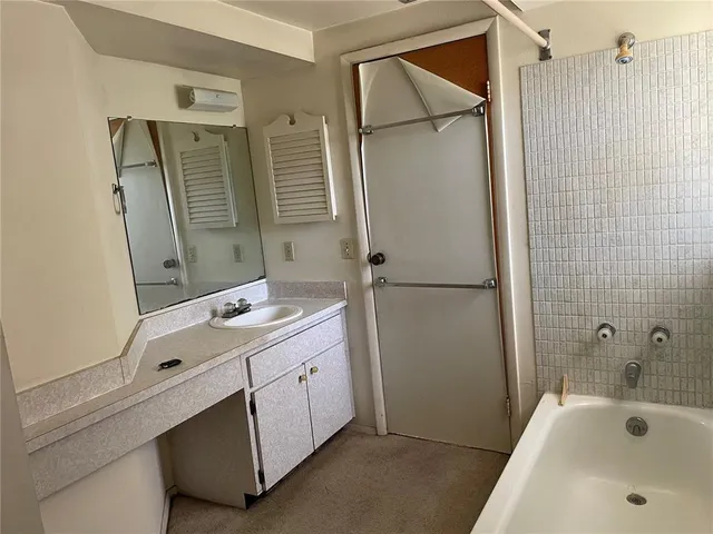 a bathroom with a tub sink and mirror