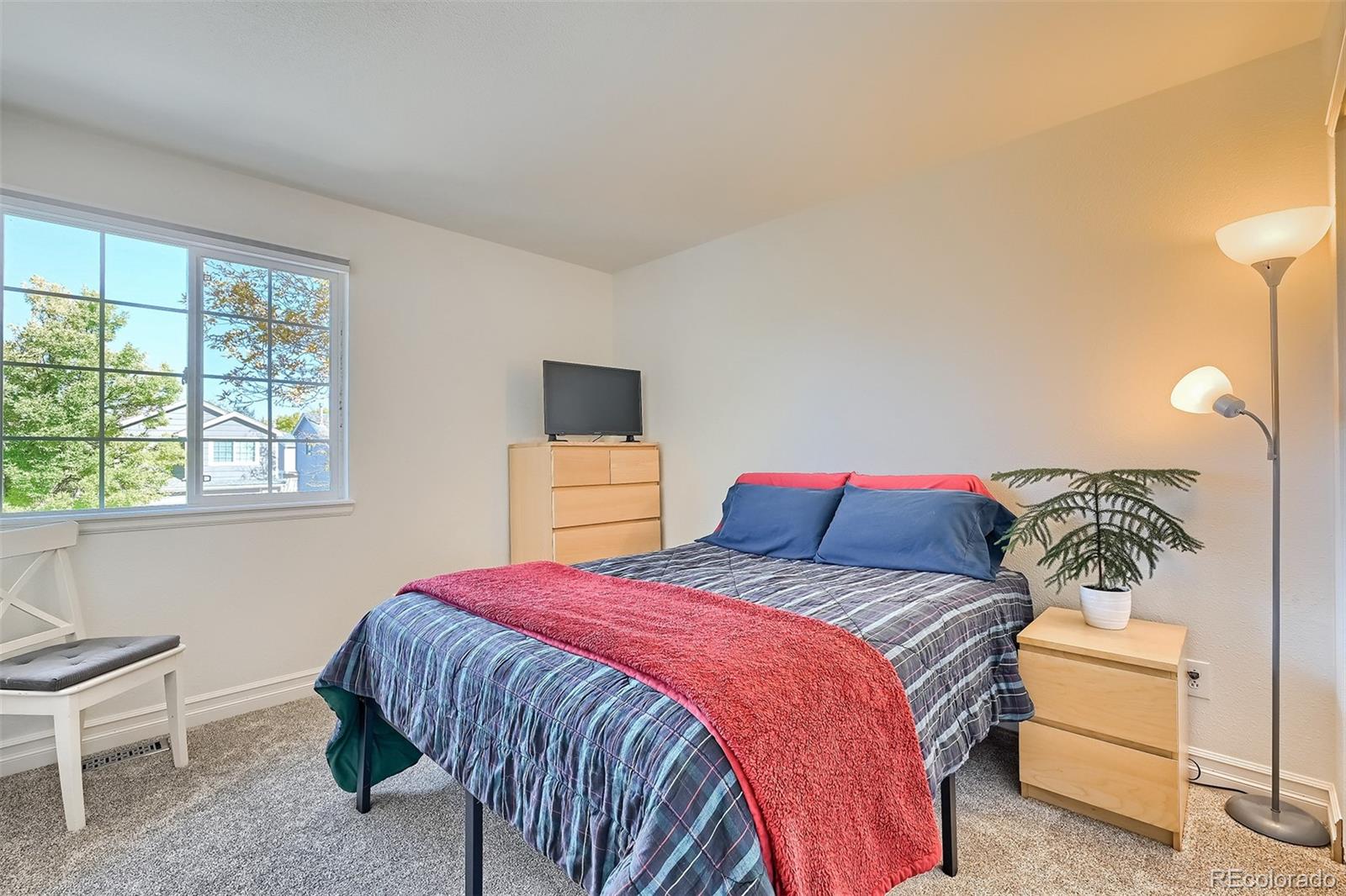 1076 Timbervale Trail Highlands Ranch, CO 80129 - Photo 22 of 29 a bedroom with a bed and a lamp on dresser