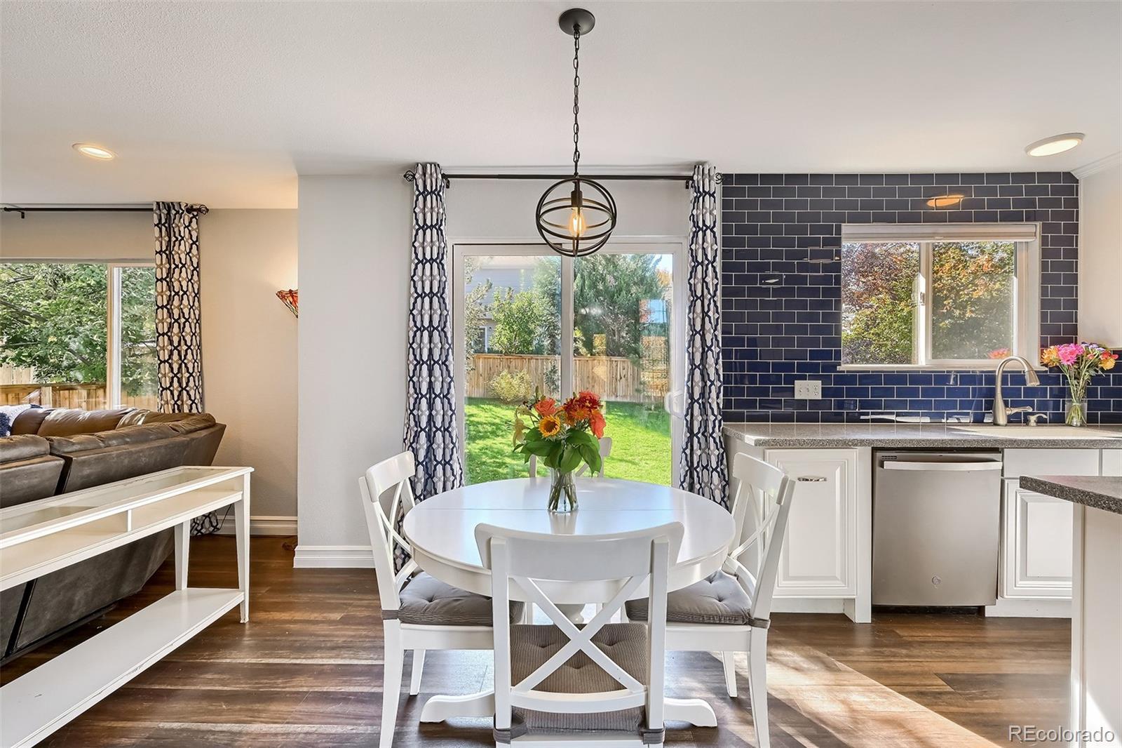 1076 Timbervale Trail Highlands Ranch, CO 80129 - Photo 5 of 29 a kitchen with stainless steel appliances granite countertop a stove a sink dishwasher a dining table and chairs with wooden floor