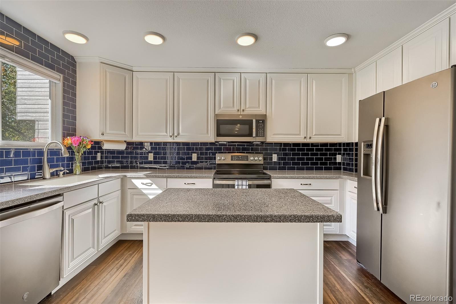 1076 Timbervale Trail Highlands Ranch, CO 80129 - Photo 7 of 29 a kitchen with stainless steel appliances granite countertop a refrigerator a stove a sink and white cabinets