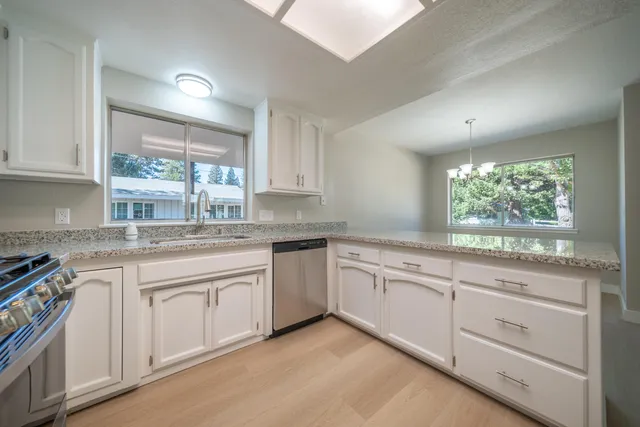 a kitchen with granite countertop white cabinets white appliances with a sink and dishwasher