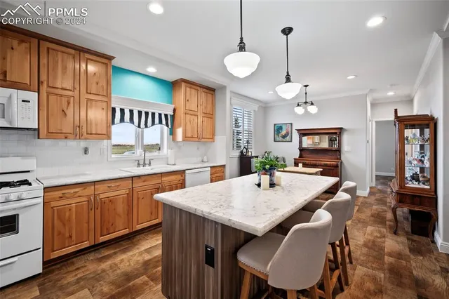 a large kitchen with granite countertop a stove a sink a dining table and chairs