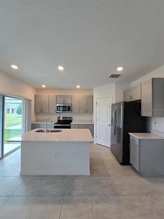 a view of kitchen with kitchen island stainless steel appliances a sink and a refrigerator