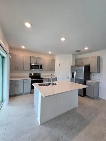 a large kitchen with stainless steel appliances a sink a counter top space and cabinets