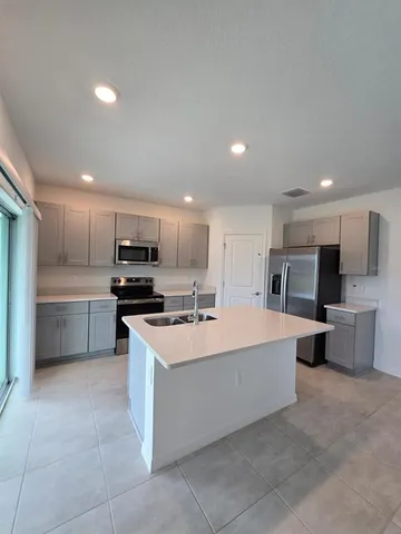 a large kitchen with stainless steel appliances a sink a counter top space and cabinets