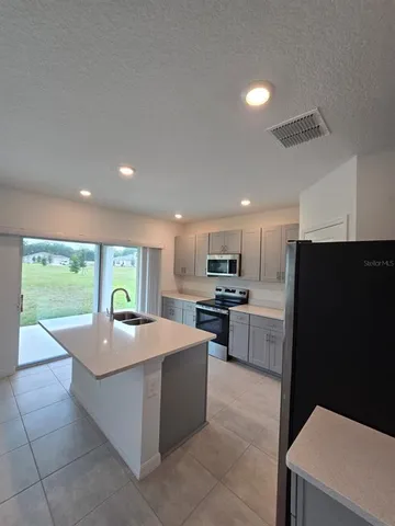 a large kitchen with kitchen island white cabinets and refrigerator