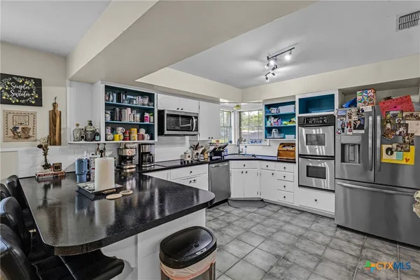 a kitchen with stainless steel appliances granite countertop a stove refrigerator and cabinets