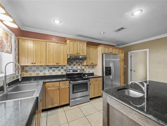 a kitchen with stainless steel appliances granite countertop a sink stove and refrigerator