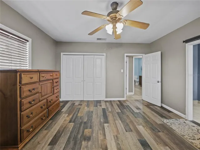 a view of a livingroom with a dresser wooden floor and a ceiling fan