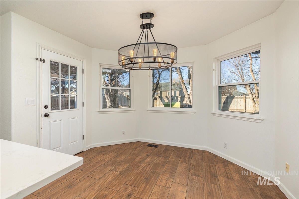 411 Hawthorne Street Nampa, ID 83686 - Photo 11 of 48 Unfurnished dining area featuring dark wood-type flooring, healthy amount of natural light, and a chandelier