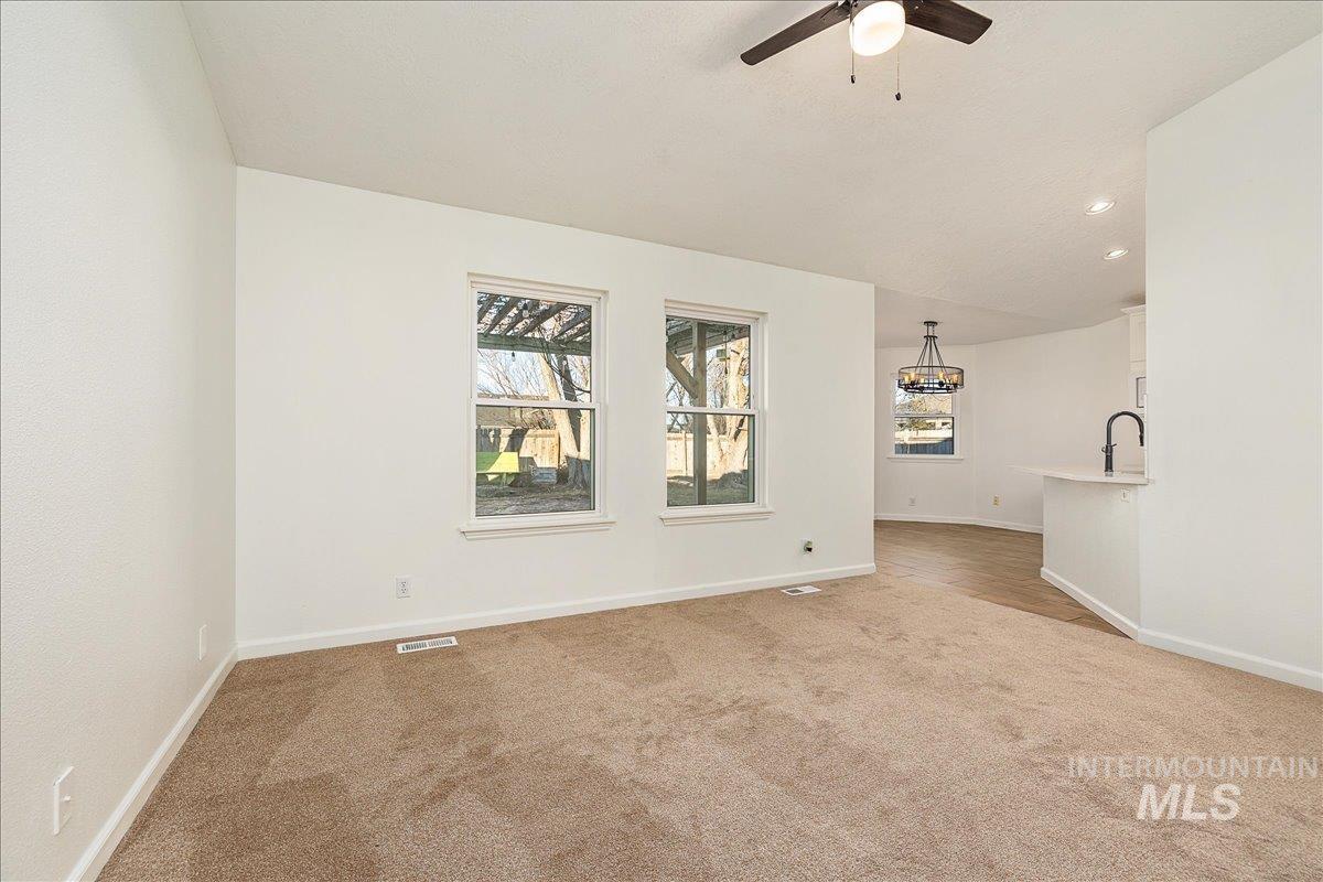 411 Hawthorne Street Nampa, ID 83686 - Photo 14 of 48 Empty room featuring light colored carpet, lofted ceiling, recessed lighting, a chandelier, and a ceiling fan