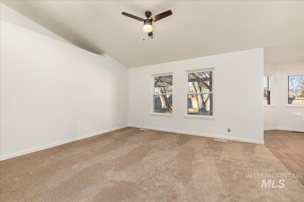 411 Hawthorne Street Nampa, ID 83686 - Photo 15 of 48 Empty room with plenty of natural light, vaulted ceiling, ceiling fan, and light carpet