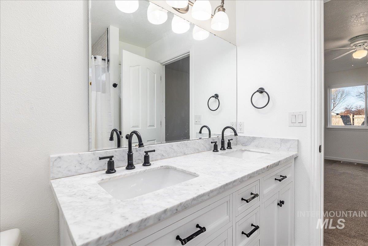 411 Hawthorne Street Nampa, ID 83686 - Photo 18 of 48 Full bath featuring curtained shower, double vanity, a ceiling fan, and dark carpet