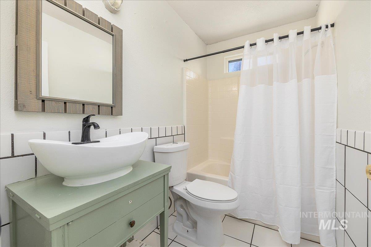 411 Hawthorne Street Nampa, ID 83686 - Photo 23 of 48 Bathroom with tile walls, a wainscoted wall, shower / bath combo, vanity, and light tile patterned floors
