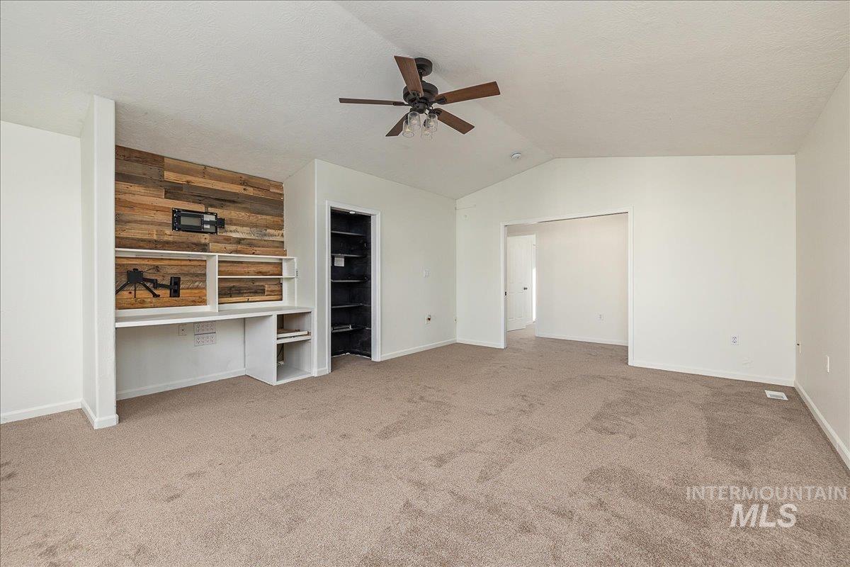 411 Hawthorne Street Nampa, ID 83686 - Photo 27 of 48 Unfurnished bedroom featuring lofted ceiling, light carpet, a ceiling fan, a textured ceiling, and wood walls