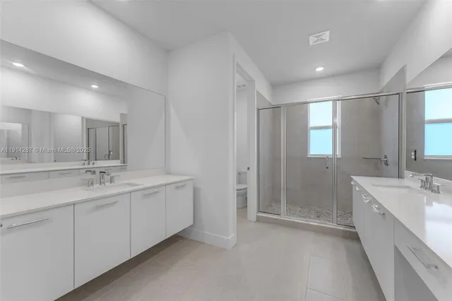 a bathroom with a double vanity sink mirror and shower