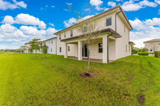a view of a white house with a big yard and potted plants