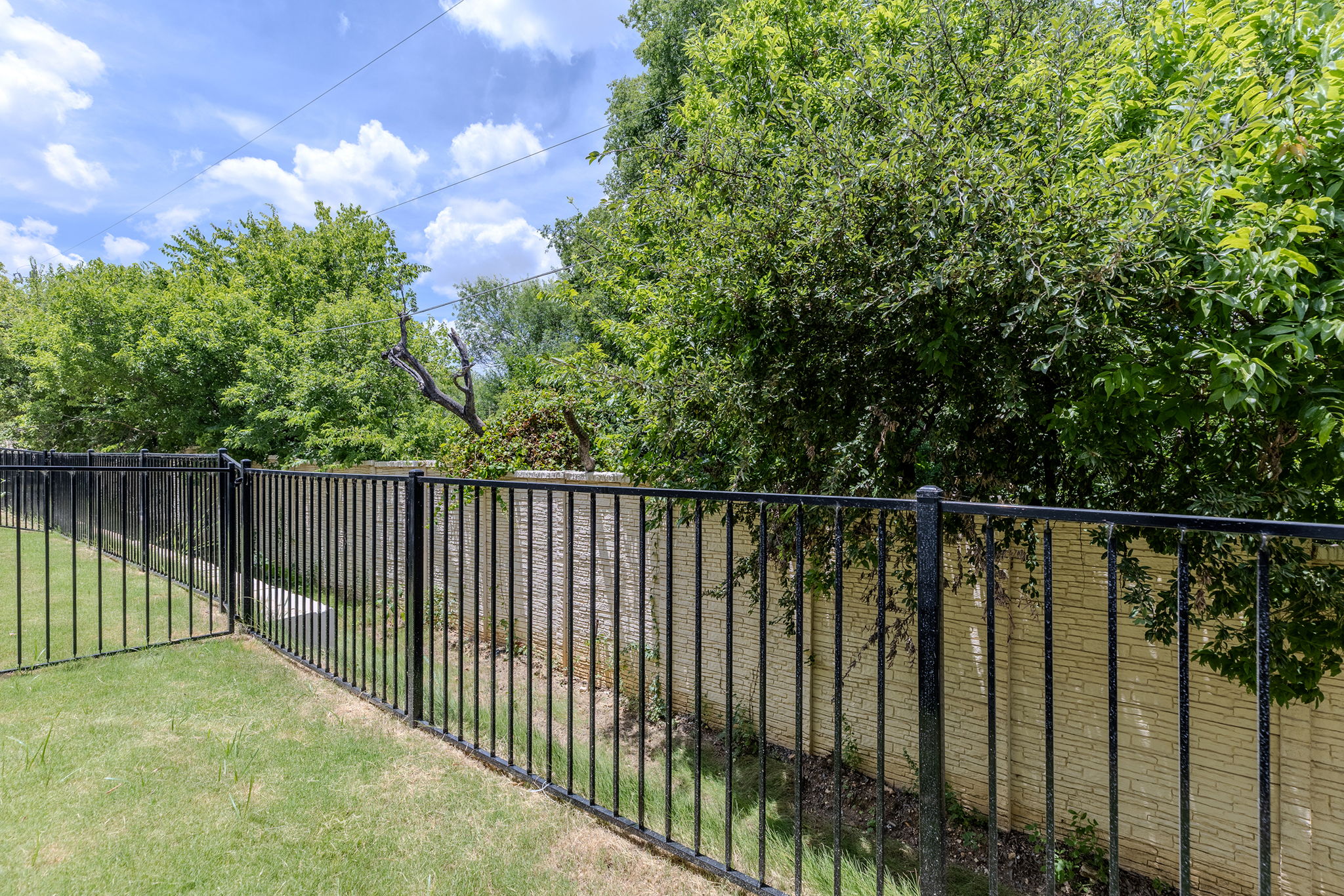 2600 Gattis School Road, Unit 1002 Round Rock, TX 78664 - Photo 35 of 40 A secured backyard oasis with mature trees and a sturdy iron fence.