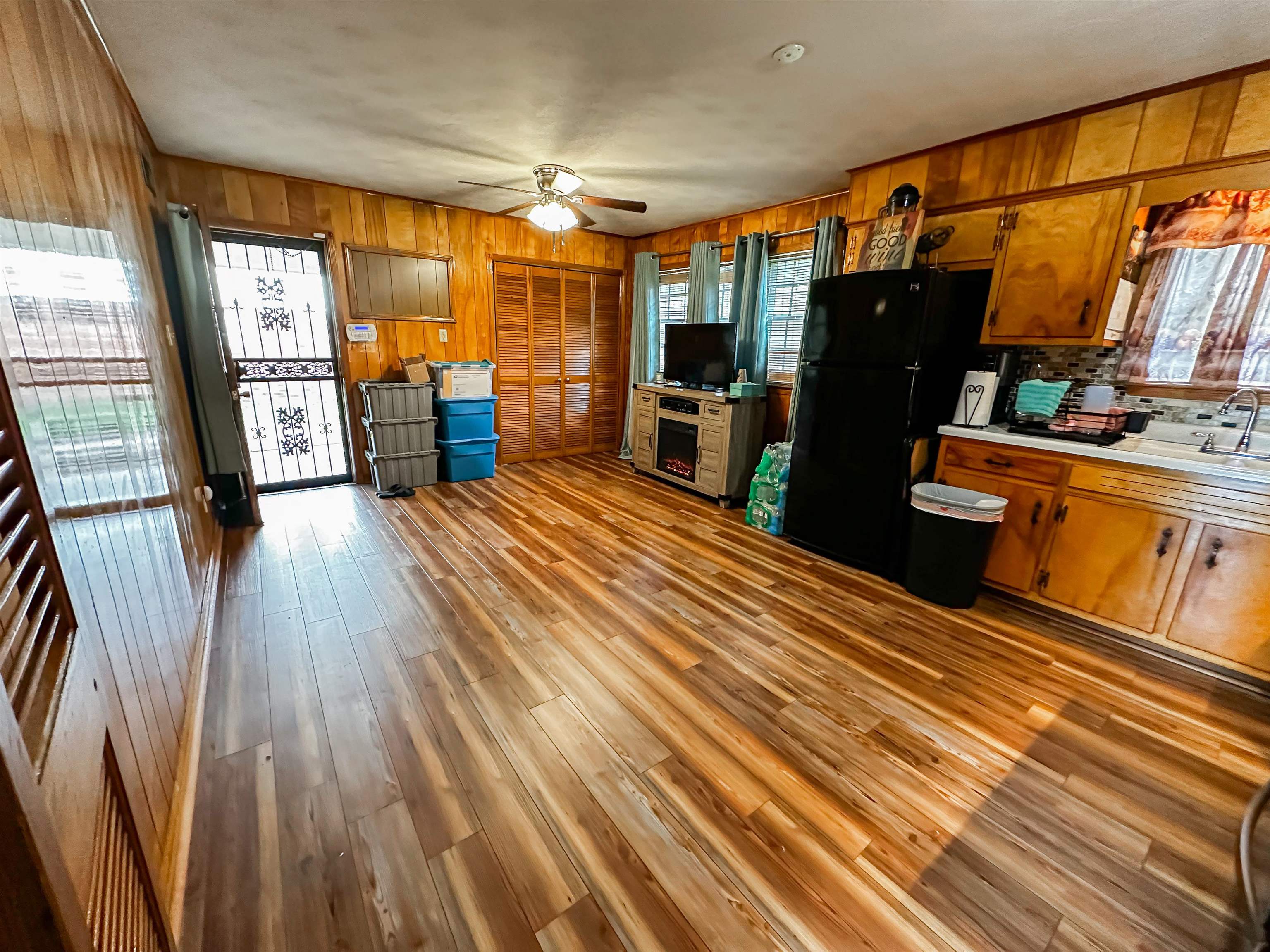 697 Shell Ln Avenue Memphis, TN 38109 - Photo 3 of 20 Kitchen with hardwood / wood-style flooring, ceiling fan, wooden walls, sink, and black fridge. Room for dining and sitting space or flex space for office space
