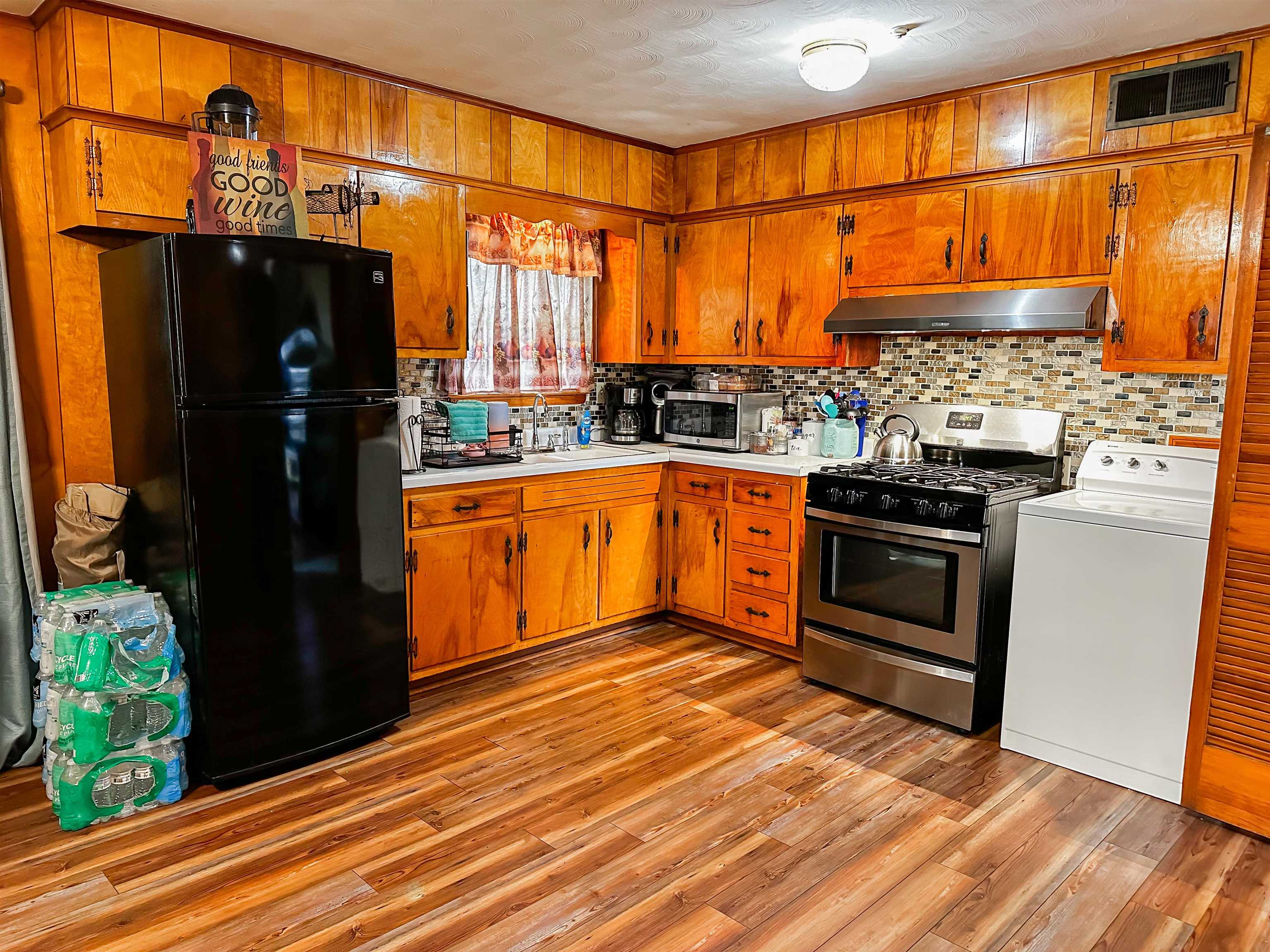 697 Shell Ln Avenue Memphis, TN 38109 - Photo 4 of 20 Kitchen featuring stainless steel appliances, sink, washer / dryer, light wood-type flooring, and wall chimney exhaust hood