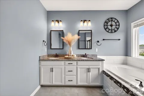 a bathroom with a granite countertop sink a mirror and a bathtub