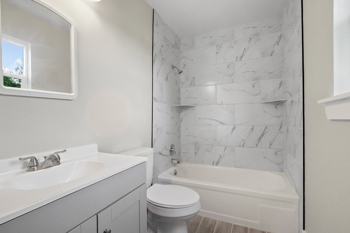 713 Burkett Street Taylor, TX 76574 - Photo 14 of 25 a bathroom with a granite countertop sink a toilet and a bathtub