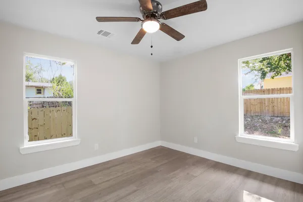 a view of an empty room with a window and wooden floor
