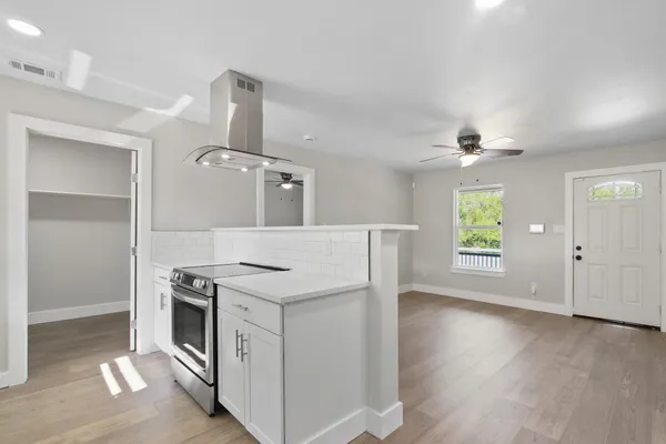 an empty room with wooden floor cabinet and windows