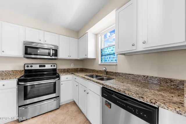 a kitchen with granite countertop a sink stove and microwave