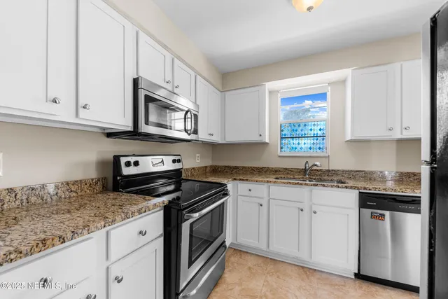 a kitchen with granite countertop cabinets stainless steel appliances and a sink