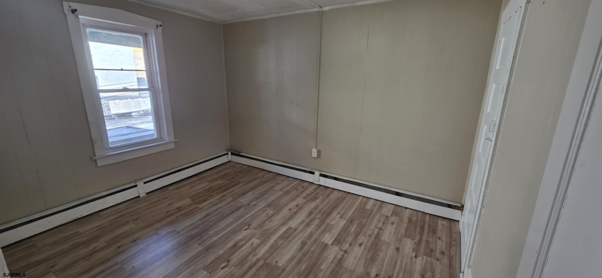 1419 Drexel Avenue, Unit 2 Atlantic City, NJ 08401 - Photo 6 of 9 a view of an empty room with wooden floor and a window