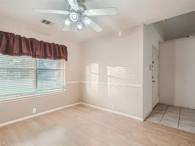 an empty room with windows and ceiling fan