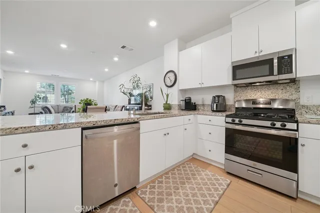 a kitchen with stainless steel appliances granite countertop a stove a sink and a microwave