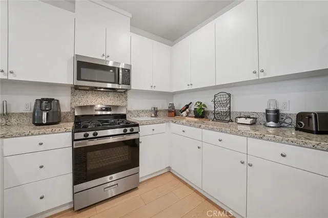 a kitchen with white cabinets and appliances