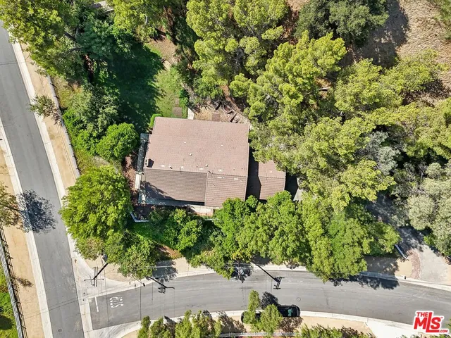 an aerial view of a house with a yard and a large tree