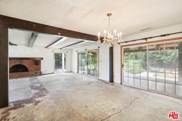 a view of a livingroom with a chandelier fireplace and large windows