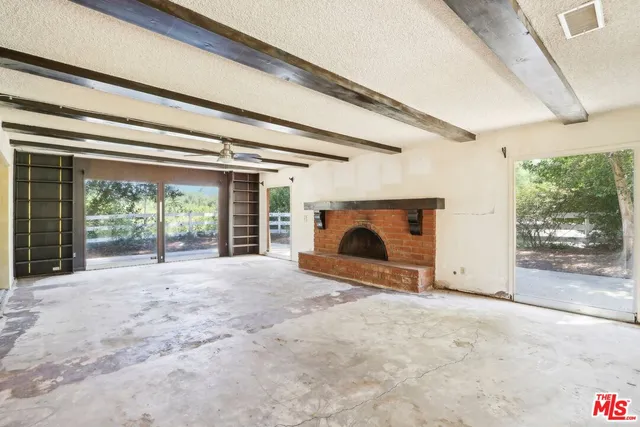a view of an empty room with a fireplace and a window