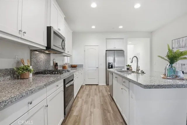 a large kitchen with stainless steel appliances granite countertop a lot of counter space and wooden floor