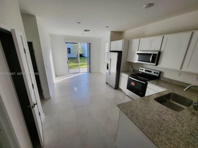 a kitchen with stainless steel appliances granite countertop a refrigerator and a stove