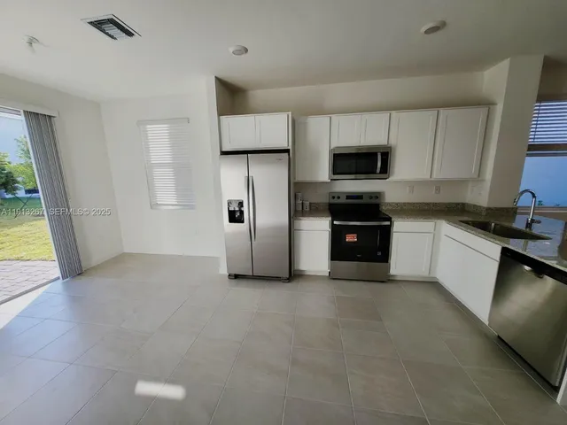 a kitchen with stainless steel appliances granite countertop a refrigerator and a stove top oven
