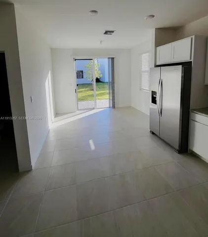 a view of an empty room with window and refrigerator