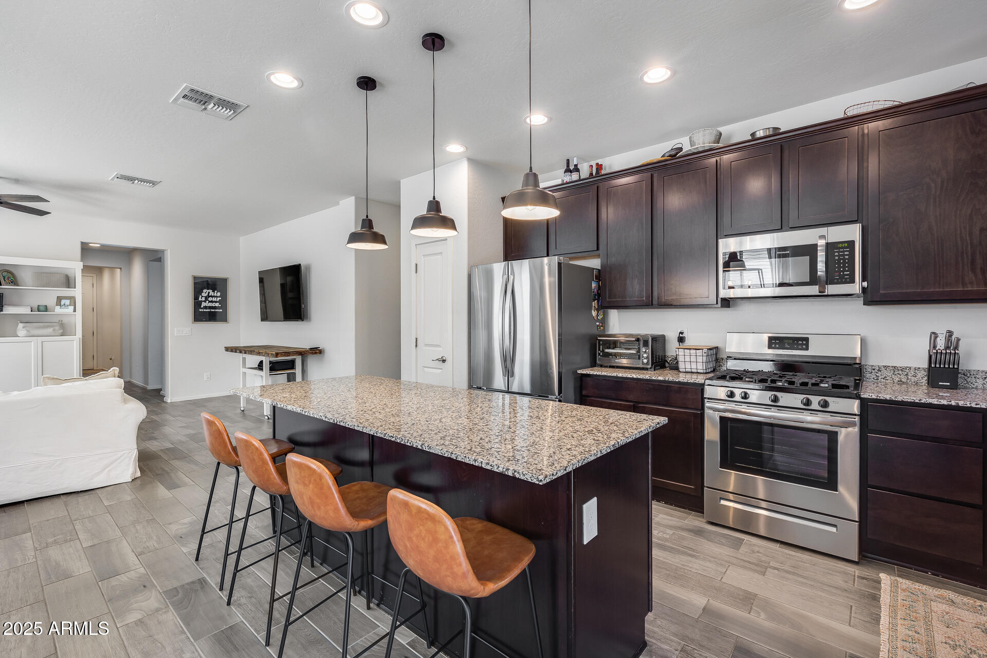 14344 West Hackamore Drive Surprise, AZ 85387 - Photo 28 of 41 a kitchen with stainless steel appliances granite countertop a stove a refrigerator a kitchen island a dining table and chairs
