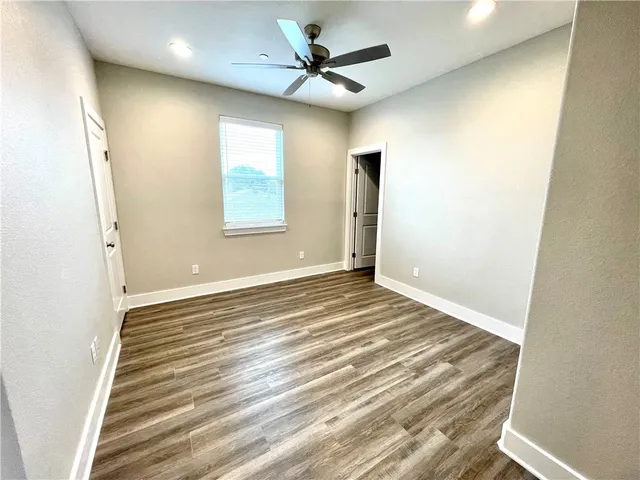 a view of an empty room with a ceiling fan and window