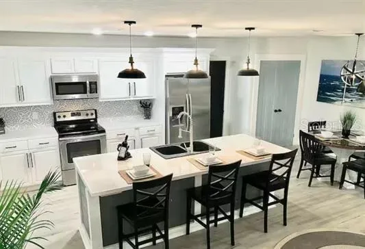 a kitchen with stainless steel appliances a dining table chairs microwave and sink