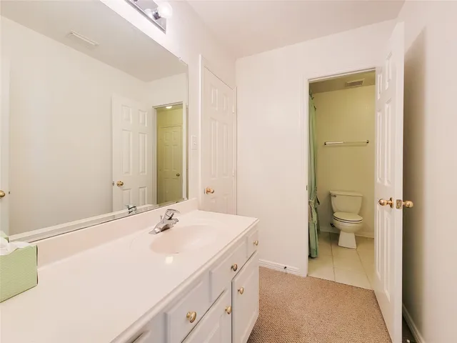 a spacious bathroom with a sink a toilet and a mirror