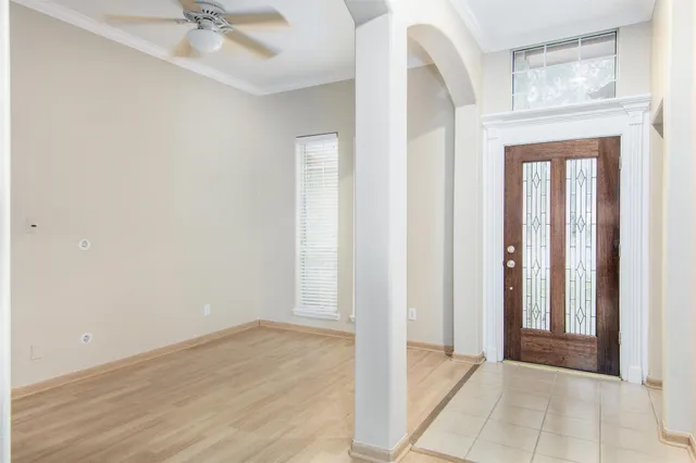 an empty room with wooden floor fan and windows